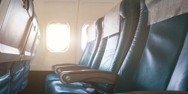 Interior of airplane with empty seats and sunlight at the window. Travel concept.