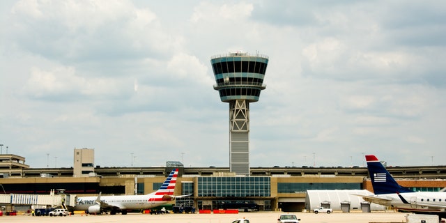 Philadelphia, PA, USA - June 23, 2014: Service vehicles speed across the tarmac under the control tower of the Philadelphia International Airport.