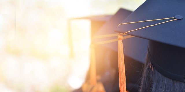 The back image of the graduates wearing a yellow tassel hat.