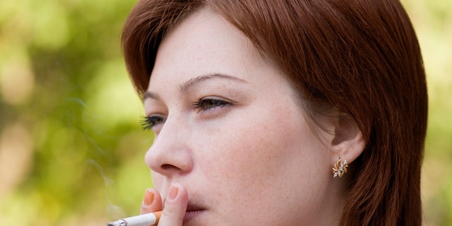 The young woman who is smoking a cigarette and carrying away a smoke in air