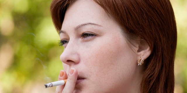 The young woman who is smoking a cigarette and carrying away a smoke in air