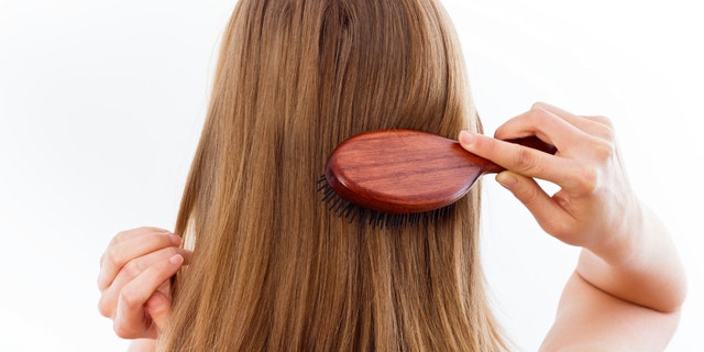 Woman combing her beautiful healthy hair.