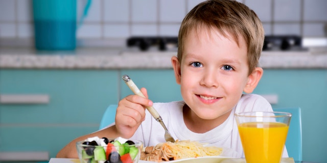 Smiling joyful boy sitting at the dinner table and looking at the camera. horizontal