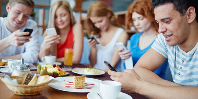 Friends sitting at café absorbed in their phones