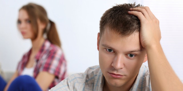 Portrait of unhappy young couple having problems. Focus on man