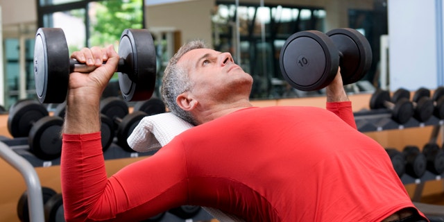 Mature man lifting dumbells at fitness gym
