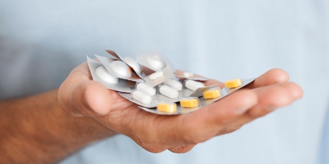 Unrecognised man holding stack of pills.