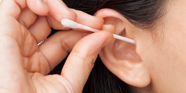 Woman cleaning ear using cotton stick