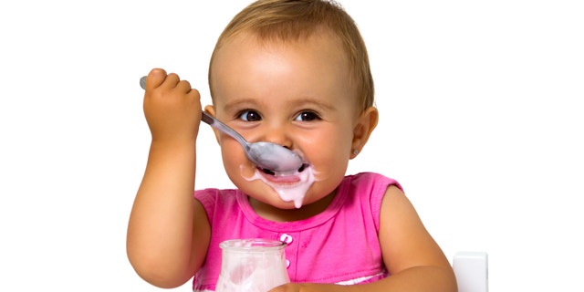girl eating yogurt isolated on white
