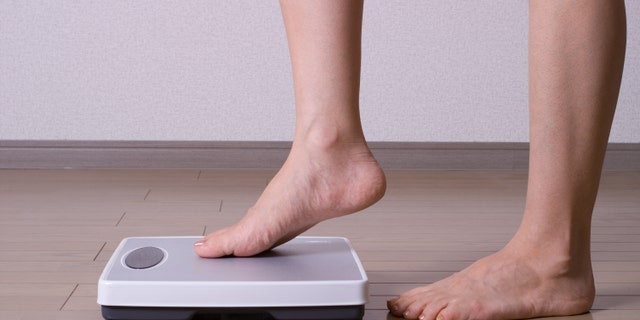 Woman stepping on scales and weighing herself