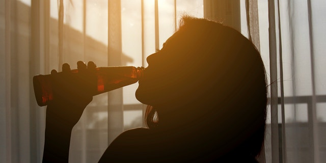 Silhouette shot of a female drinking red wine in a  room