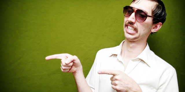 A salesman type points to at something / flirts with someone. Classy mustache and tinted sunglasses. Horizontal with copy space.