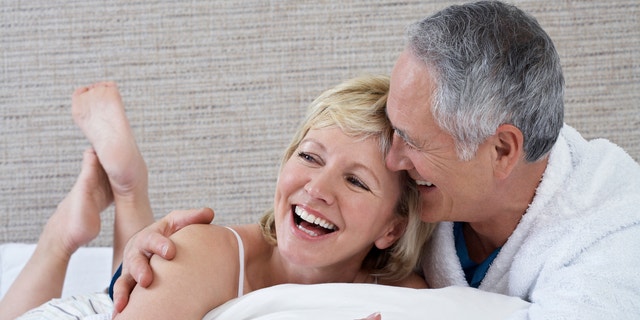 Cheerful middle aged couple lying in bed