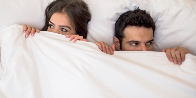 Portrait of a scared couple in bed with man and woman looking very anxious