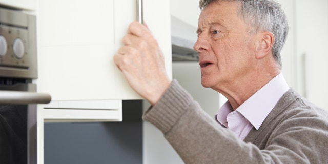 Forgetful Senior Man Looking In Cupboard