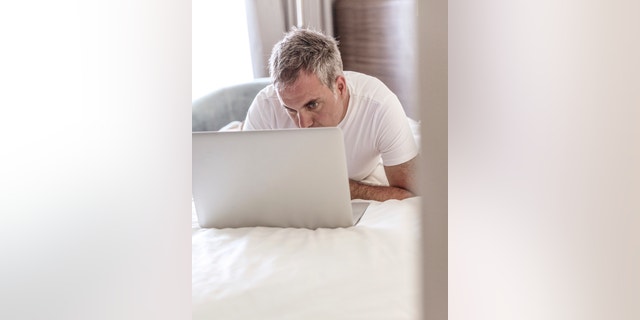 Man Using Laptop in Bed