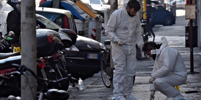 Forensic police collect evidence on the site of the explosion of a bomb in front of a bookstore in Florence, Italy, Sunday, Jan. 1, 2017. A bomb-squad officer was wounded when a suspicious package he was examining exploded. (Maurizio Degl'Innocenti/ANSA via AP)