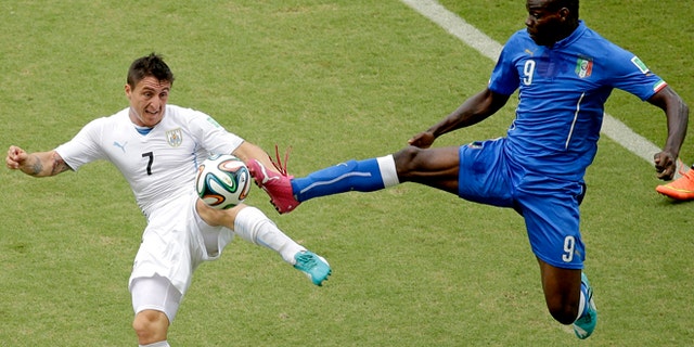 June 24, 2014: Italy's Mario Balotelli (9) and Uruguay's Cristian Rodriguez (7) battle for the ball during the group D World Cup soccer match between Italy and Uruguay at the Arena das Dunas in Natal, Brazil.