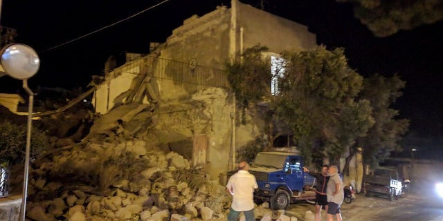 People stand near a collapsed building following an earthquake in Casamicciola on the Italian resort island of Ischia.