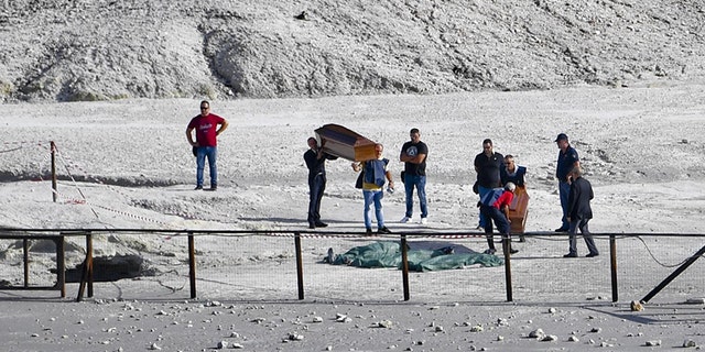 The coffins of three people who died when they fell into a crater in a steamy volcanic field in Pozzuoli, near Naples, Italy, are carried away.