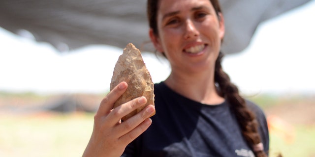 Maayan Shemer, excavation director for the Israel Antiquities Authority, showing a half-million year-old hand axe. (Samuel Magal, Courtesy of the Israel Antiquities Authority)
