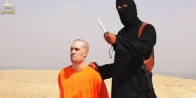 A masked Islamic State militant holding a knife speaks next to U.S. journalist James Foley at an unknown location in a still from a video posted online by the terror group.
