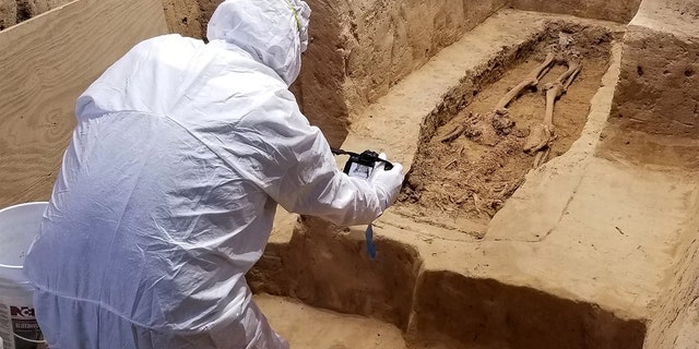 An archaeologist investigates the burial while wearing a suit that will minimize contamination to the historical site. Credit: Jamestown Rediscovery