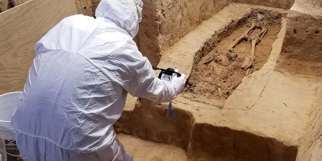An archaeologist investigates the burial while wearing a suit that will minimize contamination to the historical site. Credit: Jamestown Rediscovery