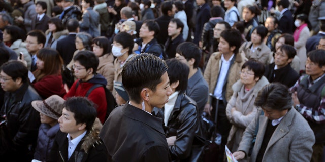 Dec. 13, 2014: A plainclothes police officer, center, stands guard as supporters and passersby listen to a speech by Banri Kaieda