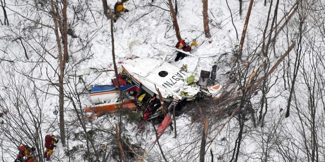 Rescuers work near the helicopter crashed in mountains in Nagano prefecture, central Japan Sunday, March 5, 2017. The rescue helicopter carrying nine people has crashed in snow-coved mountains during a training flight.
