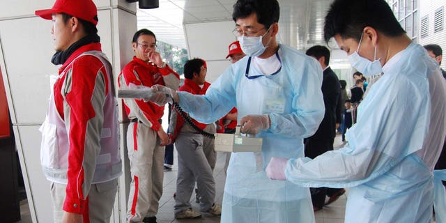 March 14: A Red Cross rescue worker, in red, is scanned for signs of radiation upon returning from Fukushima to his hospital in Nagahama, Shiga Prefecture.