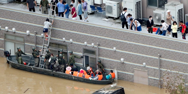 People who are stranded at a flooded hospital are rescued following heavy rain in Kurashiki city, Okayama prefecture, southwestern Japan, Sunday, July 8, 2018.