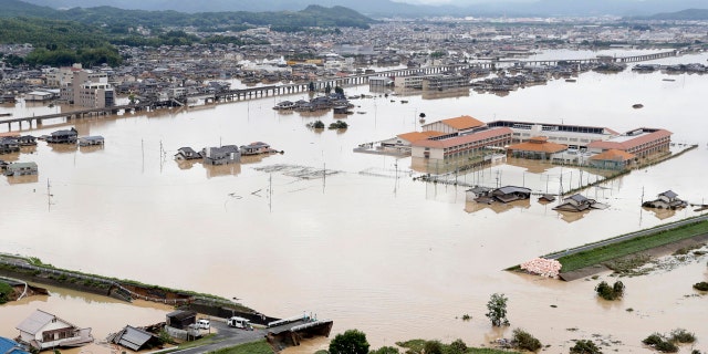 A broken embankment is seen in front in flooded Kurashiki city, Okayama prefecture, southwestern Japan, following heavy rain, Sunday, July 8, 2018