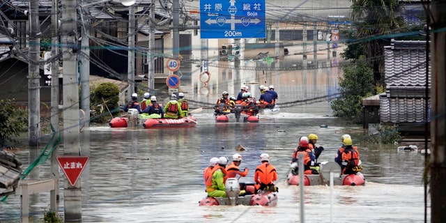 Rescuers on boats head for search in the partly submerged area in water after heavy rain in Kurashiki city, Okayama prefecture, southwestern Japan, Sunday, July 8, 2018.
