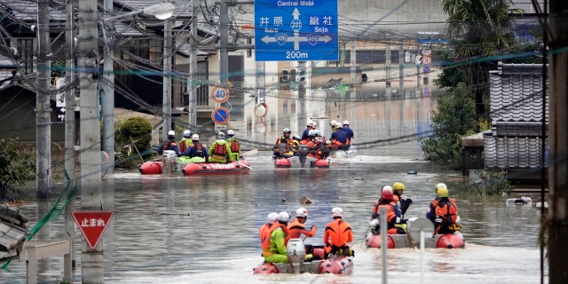 Rescuers on boats head for search in the partly submerged area in water after heavy rain in Kurashiki city, Okayama prefecture, southwestern Japan, Sunday, July 8, 2018.
