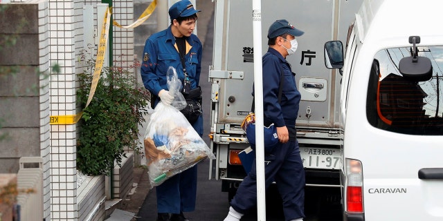 A police officer carries a plastic bag out from an apartment building where severed remains were reportedly found stored in coolers.