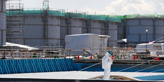 FILE 2016: A worker, wearing protective suits and masks, takes notes in front of storage tanks for radioactive water at the tsunami-crippled Fukushima Dai-ichi nuclear power plant, operated by Tokyo Electric Power Co. (TEPCO), in Okuma, Fukushima Prefecture, northeastern Japan.