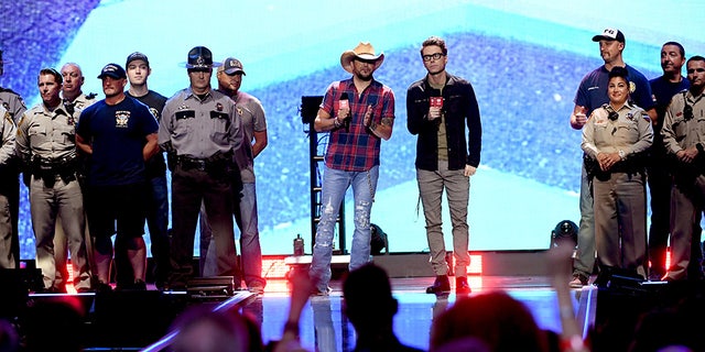 LAS VEGAS, NV - SEPTEMBER 21: Jason Aldean (center L) and Bobby Bones (center R) speak onstage with first responders during the 2018 iHeartRadio Music Festival at T-Mobile Arena on September 21, 2018 in Las Vegas, Nevada. (Photo by Kevin Winter/Getty Images for iHeartMedia)