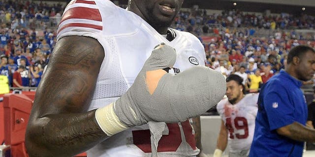 New York Giants defensive end Jason Pierre-Paul removes the bandage from his damaged hand after the Giants defeated the Tampa Bay Buccaneers 32-18 during an NFL football game Sunday, Nov. 8, 2015, in Tampa, Fla. (AP Photo/Phelan M. Ebenhack)