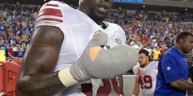 New York Giants defensive end Jason Pierre-Paul removes the bandage from his damaged hand after the Giants defeated the Tampa Bay Buccaneers 32-18 during an NFL football game Sunday, Nov. 8, 2015, in Tampa, Fla. (AP Photo/Phelan M. Ebenhack)