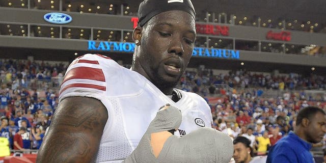 New York Giants defensive end Jason Pierre-Paul removes the bandage from his damaged hand after the Giants defeated the Tampa Bay Buccaneers 32-18 during an NFL football game Sunday, Nov. 8, 2015, in Tampa, Fla. (AP Photo/Phelan M. Ebenhack)