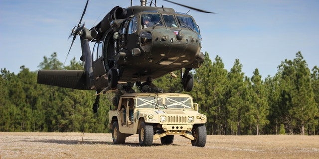 Paratroopers finish connecting a Humvee to a UH-60 Black Hawk helicopter during slingload training on Fort Bragg, N.C., Jan. 20, 2016. (Army photo by Sgt. Chad Haling)