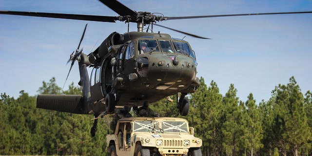Paratroopers finish connecting a Humvee to a UH-60 Black Hawk helicopter during slingload training on Fort Bragg, N.C., Jan. 20, 2016. (Army photo by Sgt. Chad Haling)