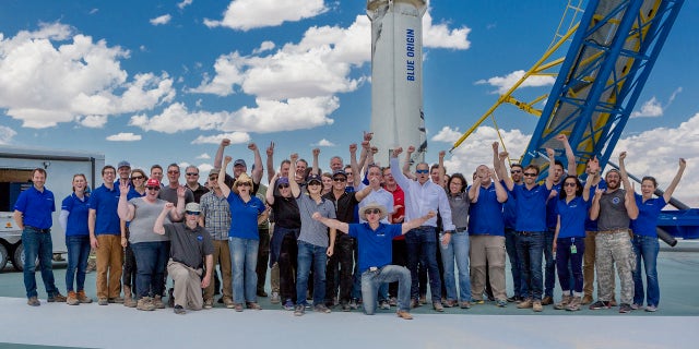 Jeff Bezos, center kneeling, takes a picture with the Blue Origin team and clients. Barnett can be seen pumping his fist above Bezos' left shoulder.