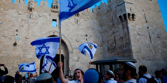 Israelis wave national flags outside the Old City's Damascus Gate, in Jerusalem.