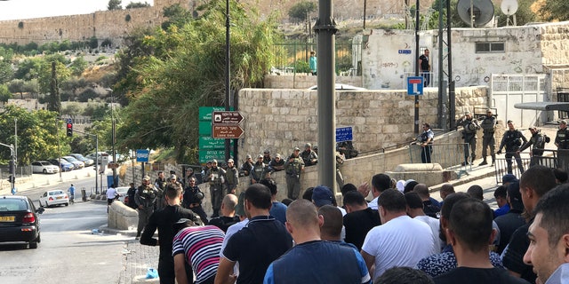 Call to prayer outside Lion's Gate entrance to Old City. Those not allowed in gather on one side of the street, police on the other.