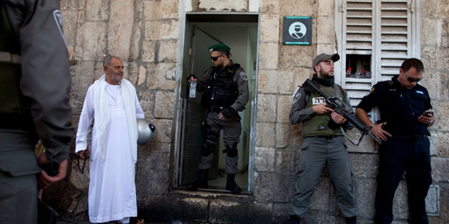 Israeli border police officers stand guard as Palestinians gather for prayer at the Lion's Gate, following an appeal from clerics for Muslims to pray in the streets instead of the Al-Aqsa Mosque compound.