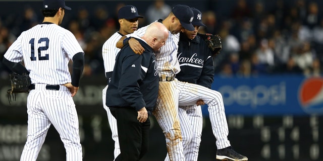 NEW YORK, NY - OCTOBER 13:  Derek Jeter #2 of the New York Yankees is carried off of the field by trainer Steve Donohue and manager Joe Girardi after Jeter injured his leg in the top of the 12th inning against the Detroit Tigers during Game One of the American League Championship Series at Yankee Stadium on October 13, 2012 in the Bronx borough of New York City, New York.  (Photo by Elsa/Getty Images)