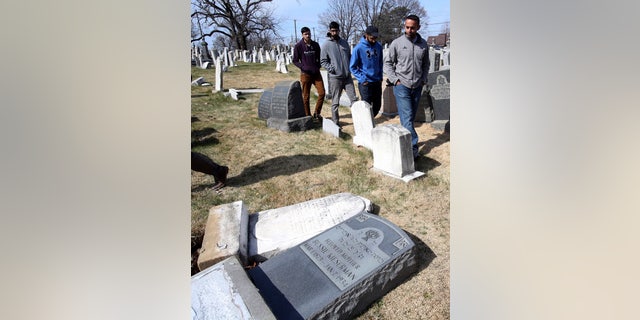 Volunteers from the Ahmadiyya Muslim Community survey damaged headstones at Mount Carmel Cemetery on Monday, Feb. 27, 2017, in Philadelphia. More than 100 headstones have been vandalized at the Jewish cemetery in Philadelphia, damage discovered less than a week after similar vandalism in Missouri, authorities said. (AP Photo/Jacqueline Larma)