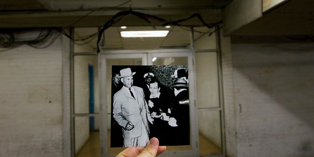 This Sept. 10, 2013 photo shows an image taken by Bob Jackson of the Dallas Times Herald on Nov. 24, 1963, of Lee Harvey Oswald, assassin of U.S. President John F. Kennedy, reacting as Dallas night club owner Jack Ruby, foreground, shoots at him from point blank range in a corridor of Dallas Police Headquarters, juxtaposed with the current scene at the Dallas Police Headquarters, in Dallas. [Associated Press)